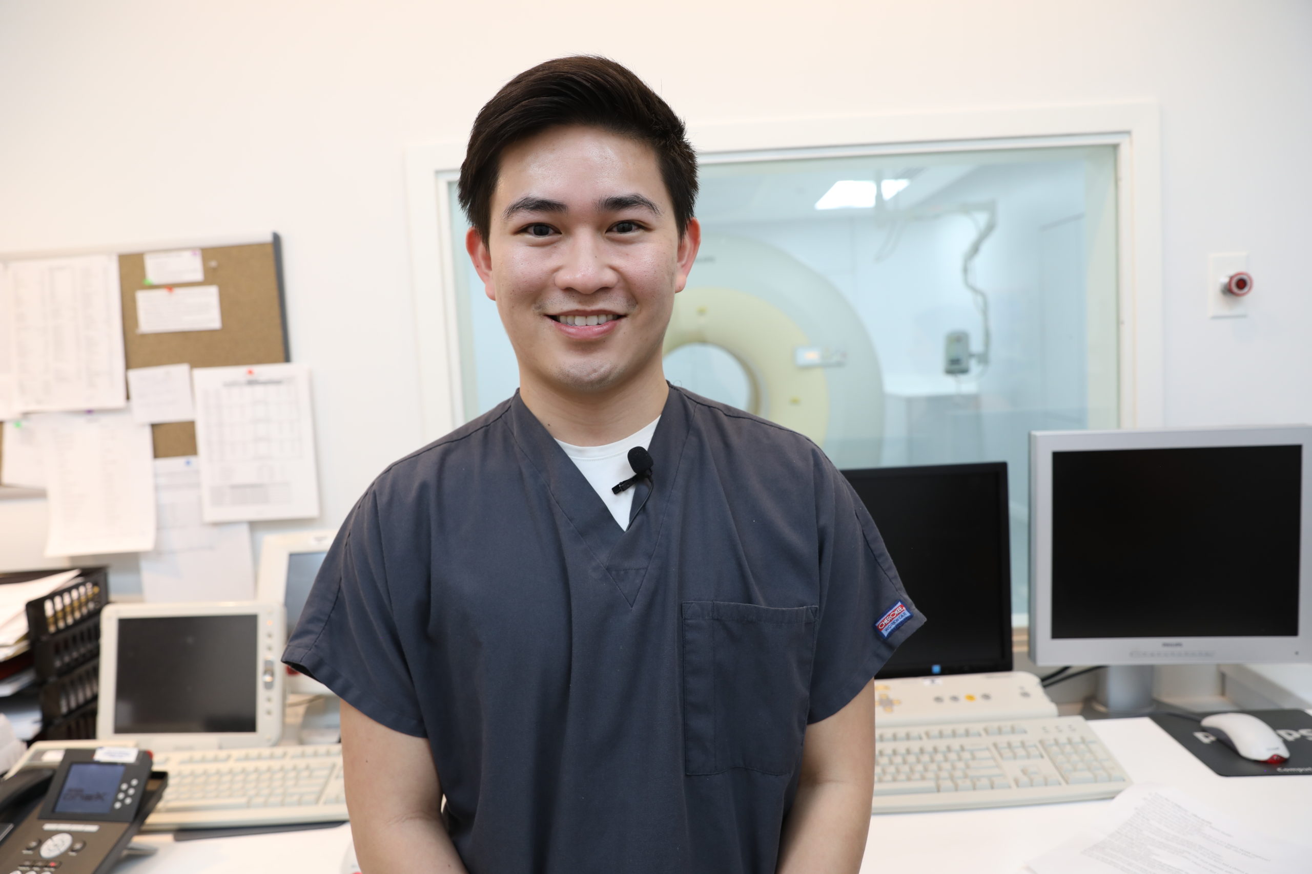 A smiling, male Baptist Health employee in an office in front of computers